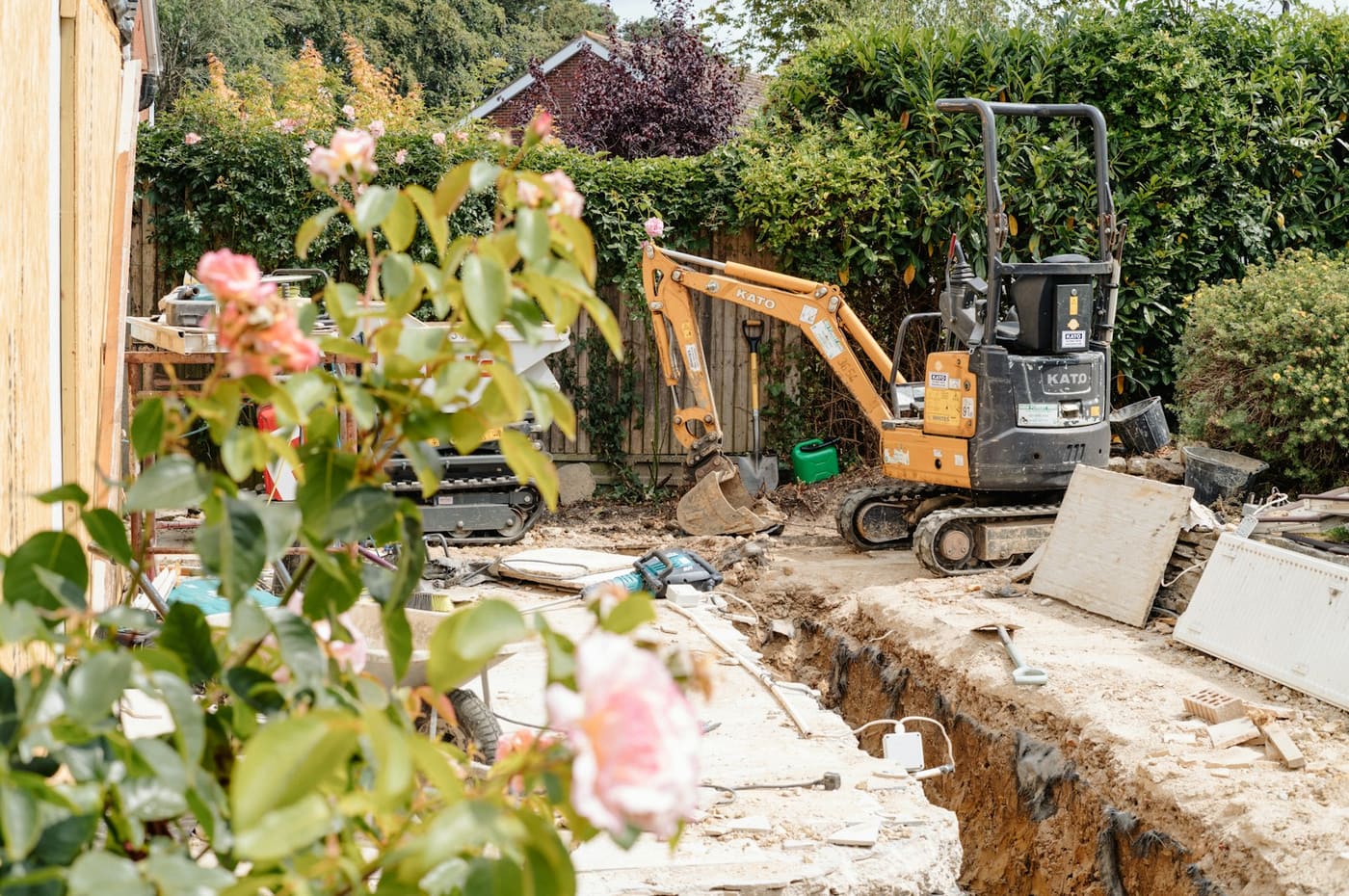 A mini excavator working in a trench on a building site.