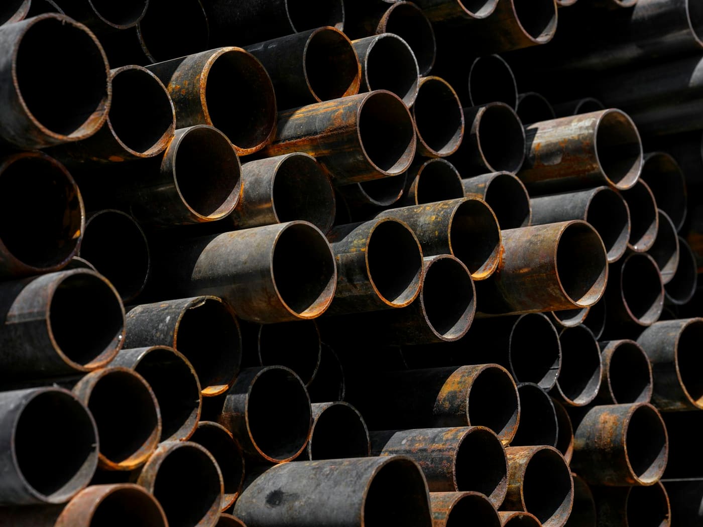 Large steel pipe stacked end-on in a yard.